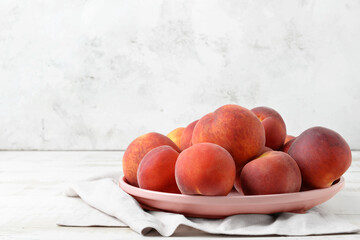 Plate with sweet peaches on table