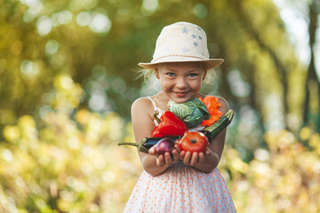Cute girl holding vegetables from the garden, fresh rural products in hands. - obrazy, fototapety, plakaty