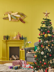 New Year interior decoration, yellow wall background, fir tree, fireplace and armchair.