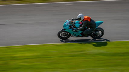 A panning shot of a racing bike cornering on a track.