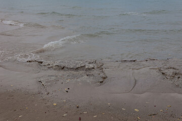 Lake water washing over worn rocks on overcast day