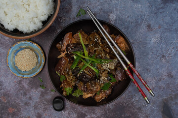 Korean vegan braised eggplant gaji namul  served in dark bowl  along with rice