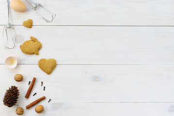 Gingerbread cookies with spices, eggs, whisk on a white wooden table. Horizontal orientation, copy space, top view.