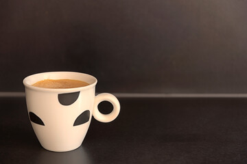 Fresh cup of coffee on dark background.