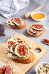 Crispy bun with cream cheese and fresh slice figs, sesame seeds and a bowl of honey