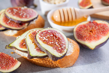 Crispy bun with cream cheese and fresh slice figs, sesame seeds and a bowl of honey
