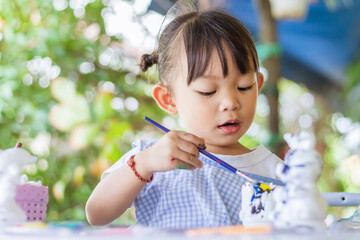 Asian student drawing and painting colours on the paper in the room. Study​ from​ home, social​ Distance, Kid and education concept. Portrait image of 2-3 yeas old child girl.