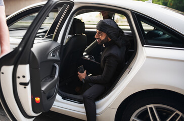 A stylish young Arabic man getting out of the luxury car.