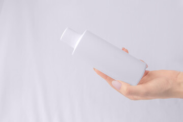 Mock up cosmetics. White bottle of shampoo, gel in a woman's hand. Copy space