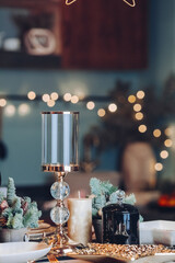 Close up of high glass candlestick on table near Christmas decoration. New Year eve concept