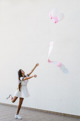 Woman with hearts and pink air balloons on bachelorette party outdoors. Beautiful sexy young girl in dress and veil on bachelor party. Maiden evening, Hen-parties. Place for text.