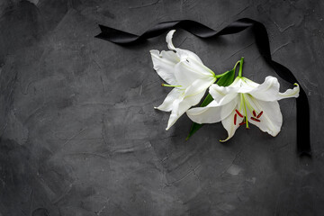 Lily funeral flower on dark stone. Condolence card with copy space - obrazy, fototapety, plakaty