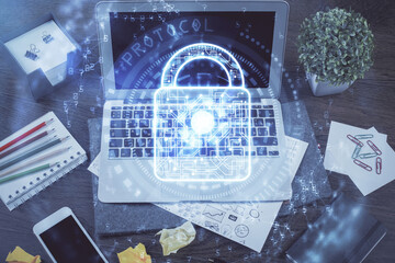 Double exposure of desktop with computer and lock icon hologram. Concept of data safety.