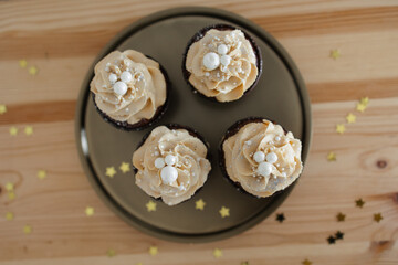 Obraz na płótnie Canvas chocolate cupcakes with caramel cream decorated with silver on a gold tray