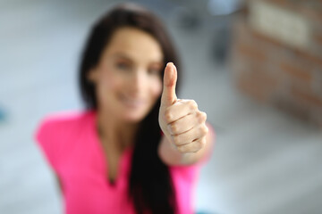 Woman in sportswear smiles and holds her thumbs up. Sport and a positive start to the day concept