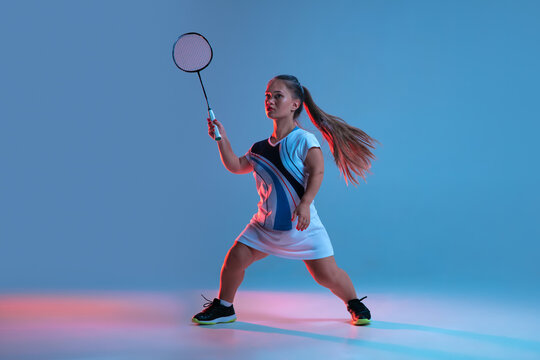 High up. Beautiful dwarf woman practicing in badminton isolated on blue background in neon light. Lifestyle of inclusive people, diversity and equility. Sport, activity and movement. Copyspace.