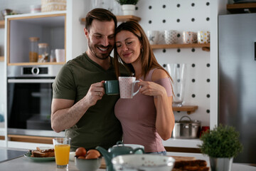 Young couple making breakfast at home. Loving couple drinking coffee in kitchen.