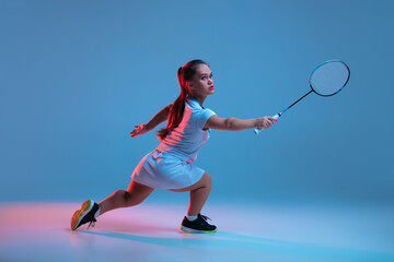 Fototapeta na wymiar Winner. Beautiful dwarf woman practicing in badminton isolated on blue background in neon light. Lifestyle of inclusive people, diversity and equility. Sport, activity and movement. Copyspace.
