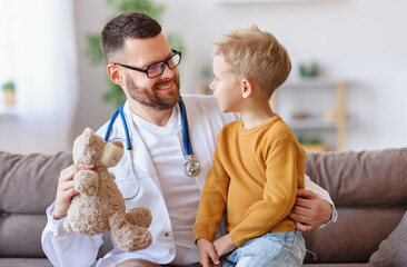 friendly pediatrician doctor shows Teddy bear to patient little boy.