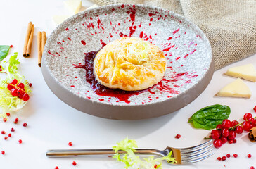 Baked camembert with lingonberry sauce on a gray ceramic plate in a restaurant. Decor