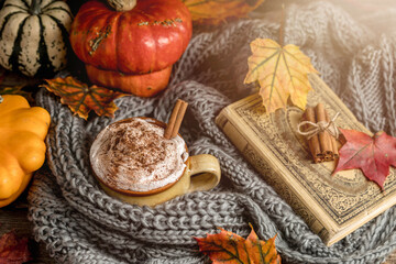 Autumn concept, still life of pumpkin spice latte with whipped milk cream and cinamon. Colorful pumpkins and dry leaves. Old natural wood backround