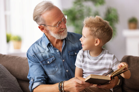 Happy grandfather reading book to grandson.