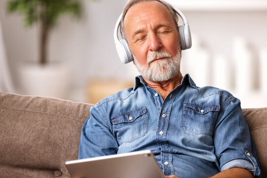 Senior  man listening to music sitting on sofa.