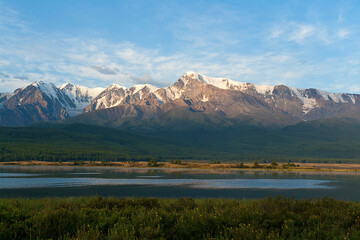 Panorama of a mountain lake against the background of snow-capped peaks. Reflection in water. Altai, Russia.