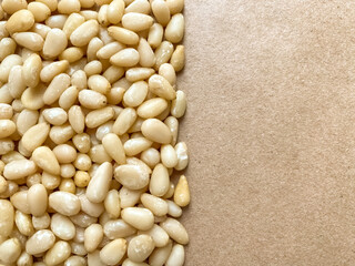 Peeled pine nuts on kraft paper background with blank space for text, copy space. Top view