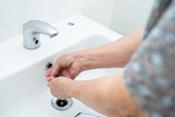 Asian senior elderly old lady woman patient washing hands in toilet bathroom the hospital ward, healthy medical concept