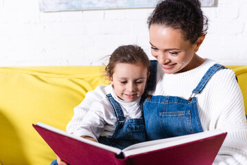 Mother embracing daughter reading book at home