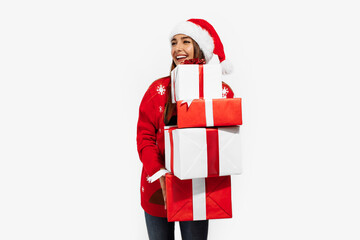 beautiful brunette in red sweater and Santa Claus hat holding many gifts on white background, Christmas, holiday concept
