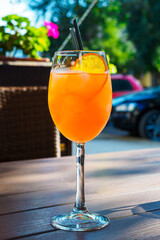 cocktail aperol spritz with a slice of orange on a wooden table on the summer veranda of a cafe in...