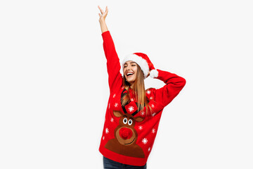 Excited young woman in christmas sweater and santa claus hat, having fun on white background