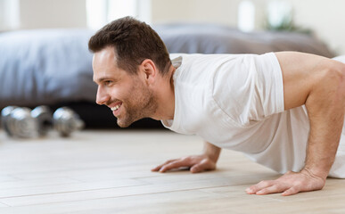 Obraz premium Sporty Man Doing Plank Exercise On Floor Training At Home