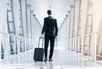 Rear view of tall businessman walking by airport terminal