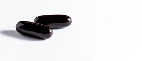 Big black soft gel medical capsules  on white background. Long banner format. Health care and immunity support concept.