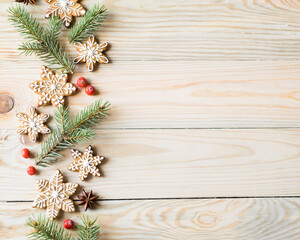 Gingerbread cookies snowflakes with fir-tree branches and berries on wooden background. Christmas, New Year and winter holidays concept. Top view, horizontal orientation, copyspace
