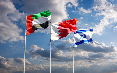 Flags of Israel, UAE and Bahrain together against the sky background. Jerusalem, Abu Dhabi and Manama signed a historic deal to normalize interstate diplomatic, economic and trade relations.