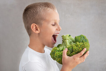 Child boy eat big fresh broccoli