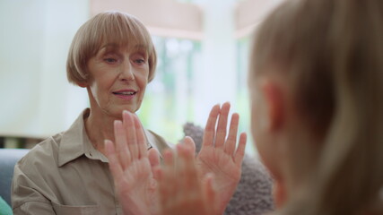 Happy grandmother teaching granddaughter to play patty cake game with hands