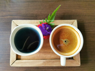 top view of coffee and herbal tea on wooden tray on brown wooden background
