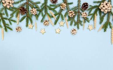 Green Christmas tree branches with New year's toys. Cones, bows and Gold stars on a sky-blue...