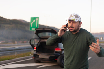 Frustrated and angry man calls roadside assistance by phone. Car problem.