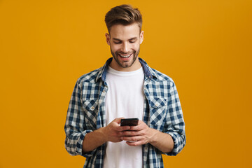 Cheerful handsome guy smiling and using mobile phone