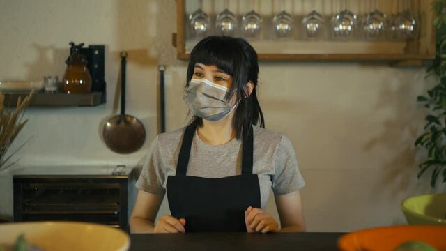 Caucasian waitress wearing protective face mask giving bag to customer in a restaurant. Young woman worker working with take away orders during corona virus outbreak. Concept food and drinks takeaway.