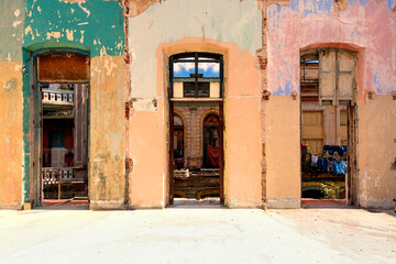 Fototapeta na wymiar Orange and purple colored rough picturesque walls with an open floor in front and with old windows in Havana Cuba.
