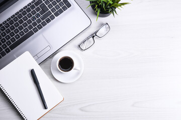 Top view of office work space, wooden desk table with laptop notebook,keyboard ,pen,eyeglasses,phone,notebook and cup of coffee.With copy space, flat lay.Mock up.