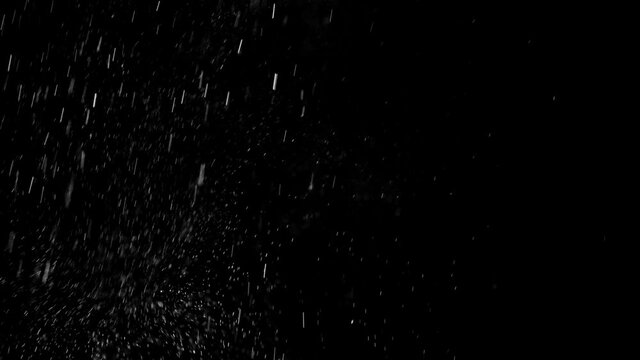Small white particles randomly fly on black background like snowflakes in winter. Abstract dynamic flying light elements on dark. Effects of snow to overlay layers in video, actual shooting in studio