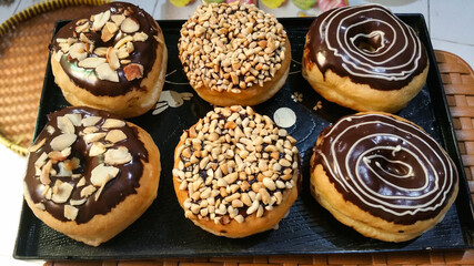 Homemade variation of chocolate donuts on the blackplate. Decorated with delicious chocolate, nuts...